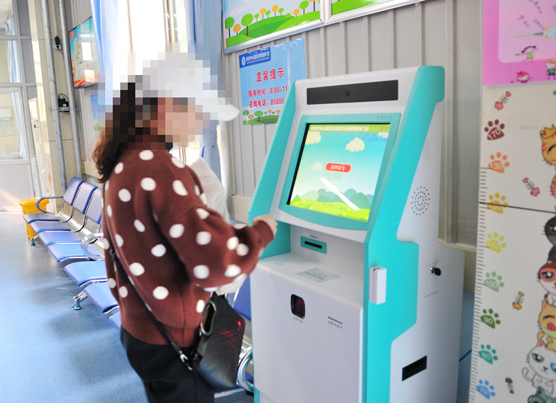 1-3 儿童家长在叫号机前取号.jpg
